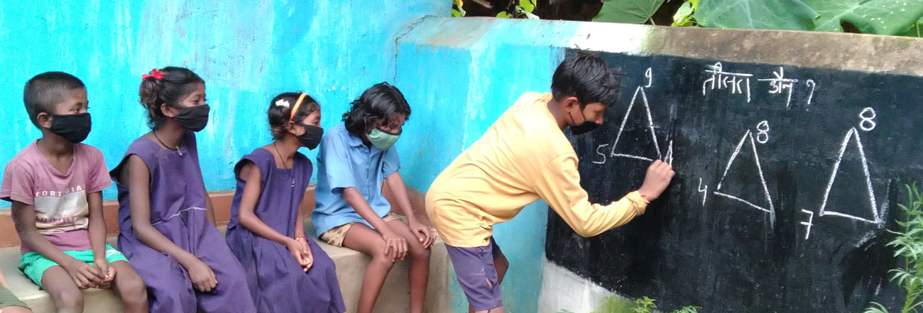 Student writes on chalkboard in front of other students. 